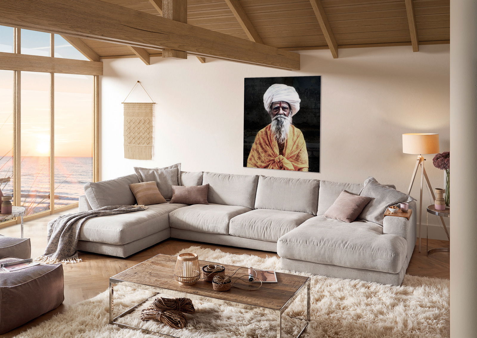 Pure Home Lifestyle Wohnlandschaft PURE 979 Gemütliche Polsterrundecke in einem modernen Wohnzimmer mit Blick auf das Meer durch große Fenster, dekoriert mit Kissen und Decken, aus der Perspektive von vorne links.