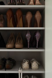 Schuhschrank mit verschiedenen Schuhen, darunter High Heels und Turnschuhe, aus frontaler Perspektive.