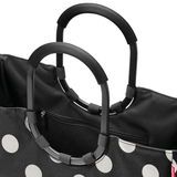 Nahaufnahme einer schwarzen Tasche mit weißen Punkten und schwarzen, ovalen Griffen.