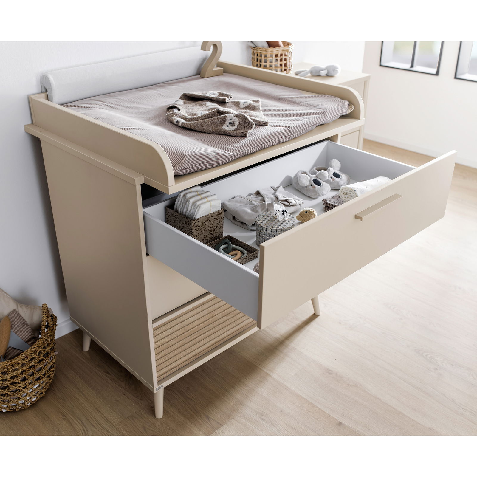 Wickelaufsatz schmal in einem modernen Kinderzimmer, seitliche Perspektive mit geöffneter Schublade, gefüllt mit Babyartikeln.