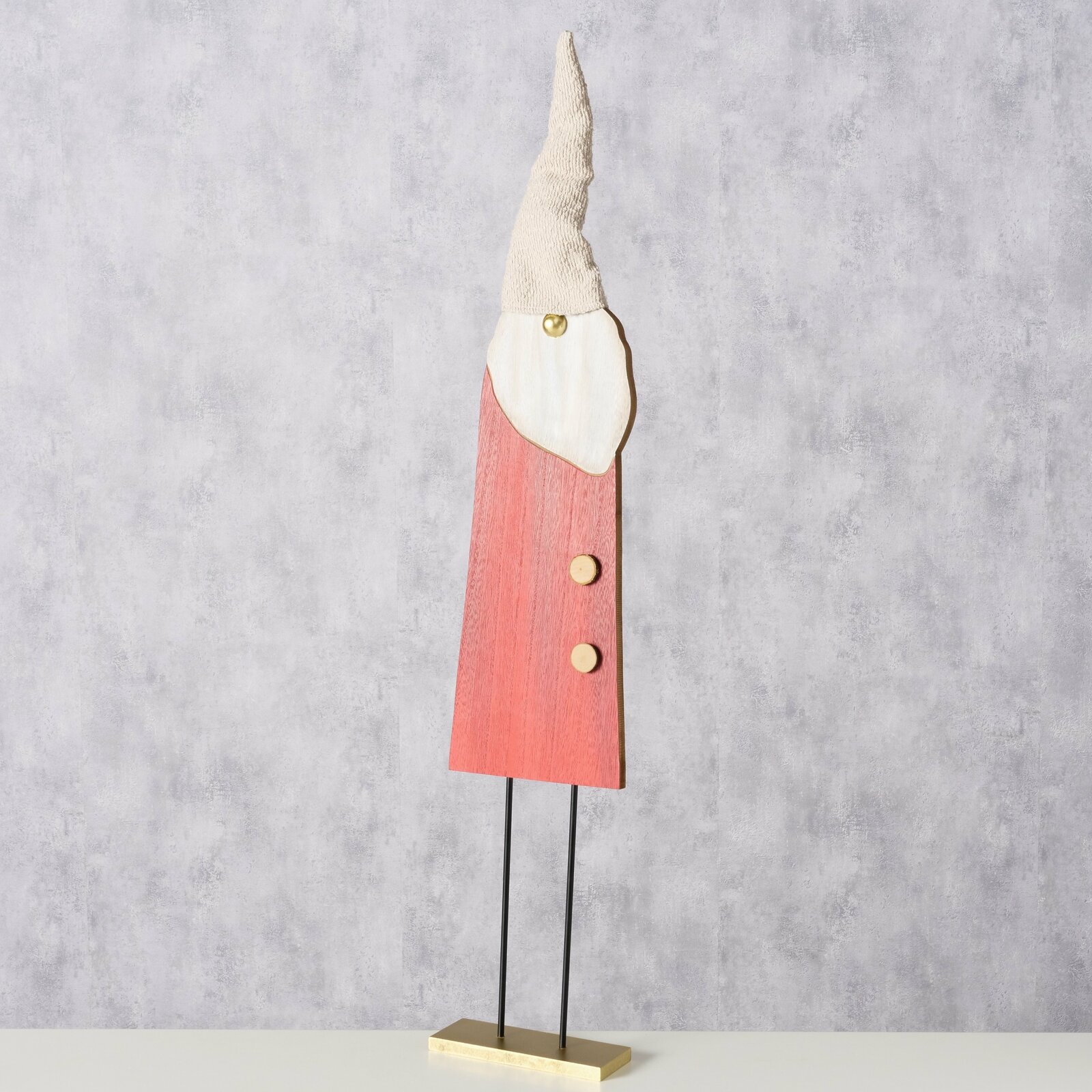 Holzfigur eines Gnomes mit rotem Mantel und spitzer Mütze, frontal fotografiert.