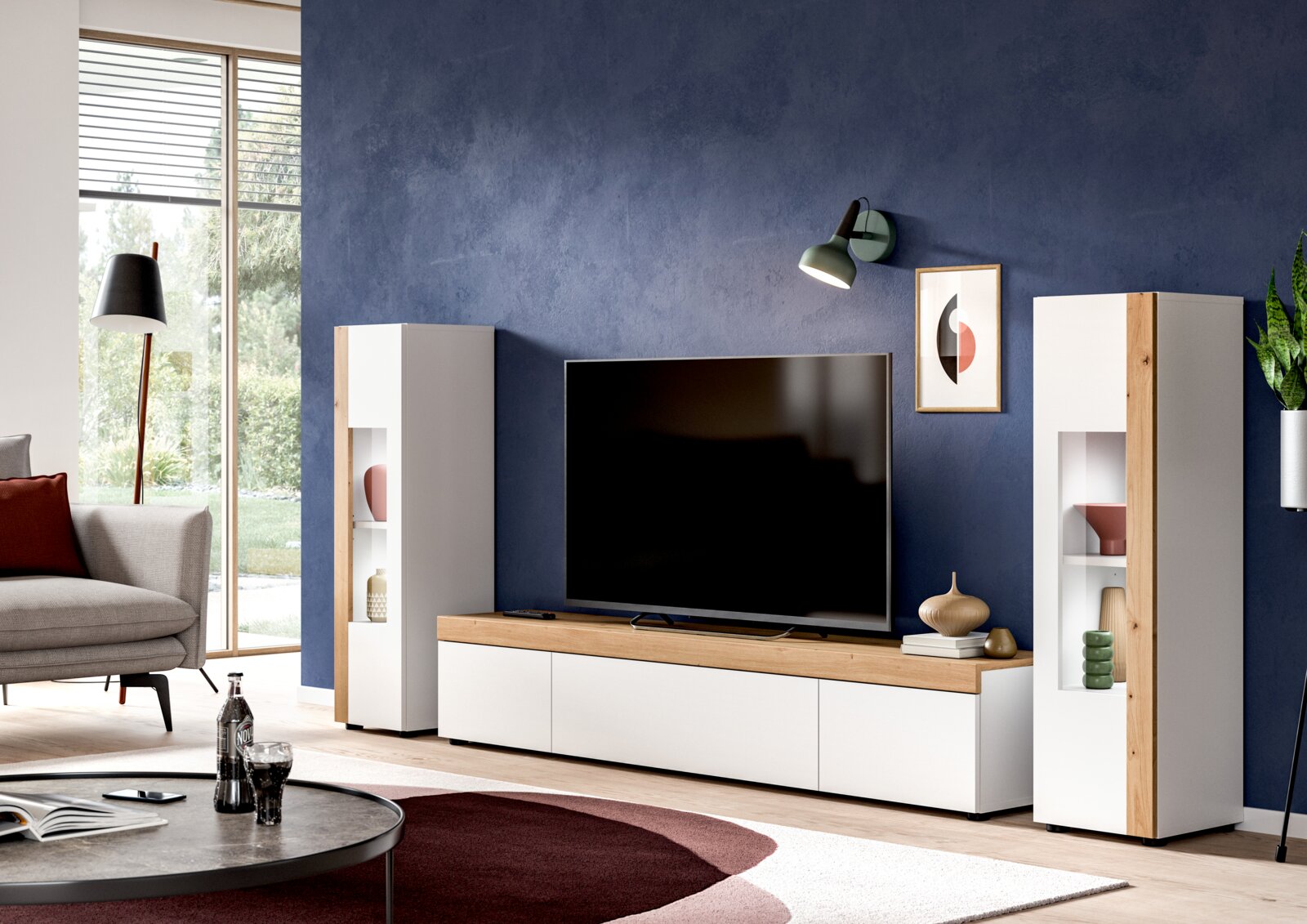 Wohnkombination mit zwei weißen Schränken und einem TV-Schrank in Holzoptik, frontal betrachtet in einem modernen Wohnzimmer mit blauer Wand.
