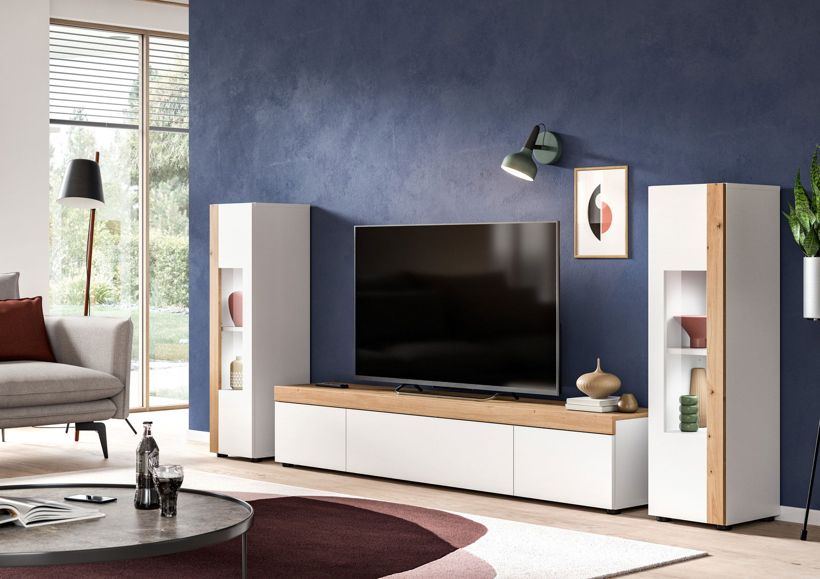 Wohnkombination mit zwei weißen Schränken und einem TV-Schrank in Holzoptik, frontal betrachtet in einem modernen Wohnzimmer mit blauer Wand.