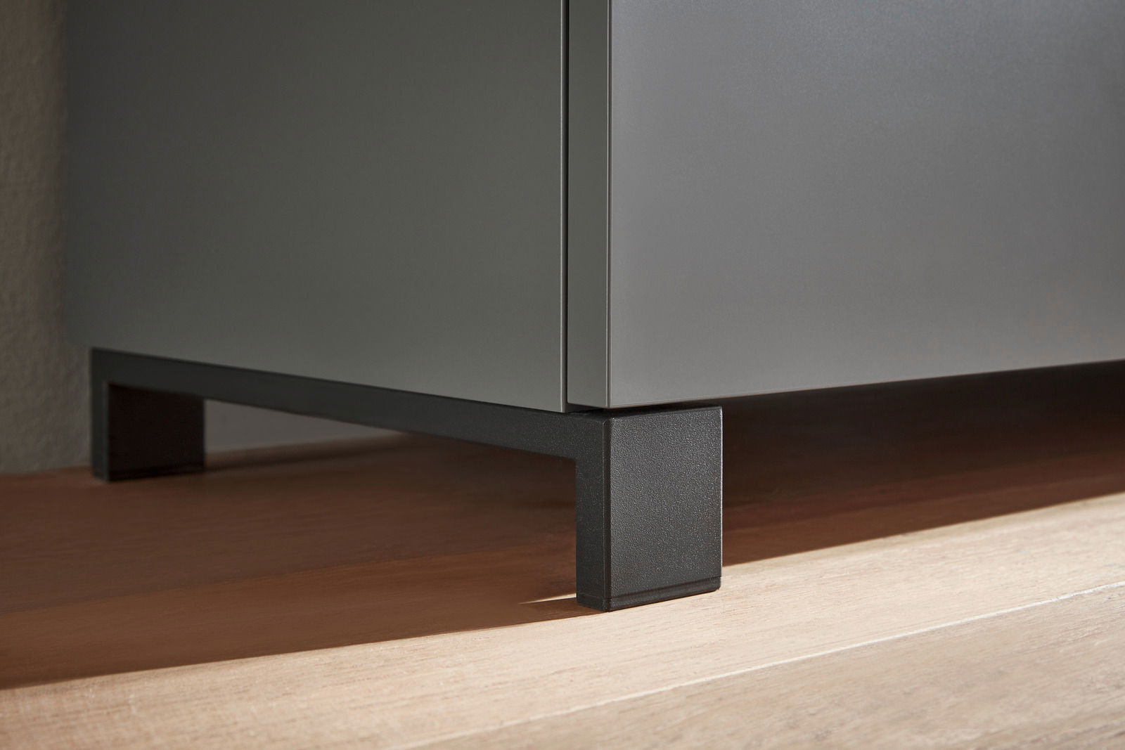 Nahaufnahme eines modernen Garderoben-Sets mit schwarzem Metallfuß auf Holzfußboden, seitliche Perspektive.