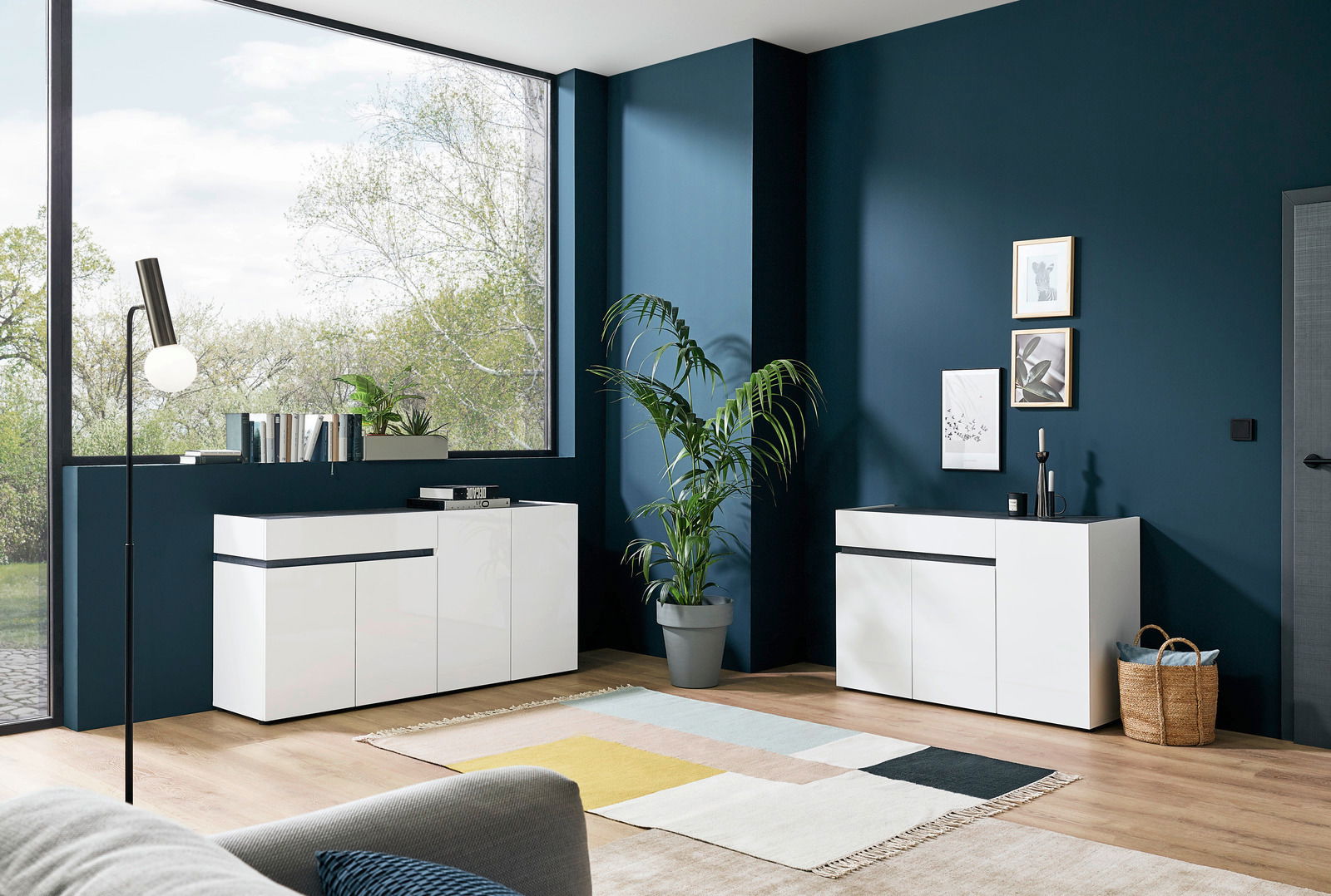 Moderner weißer Sideboard in einem stilvollen Wohnzimmer mit großen Fenstern und Pflanzen, seitliche Perspektive
