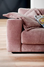 Nahaufnahme eines rosa Cord-Sofas mit Kissen, seitliche Perspektive