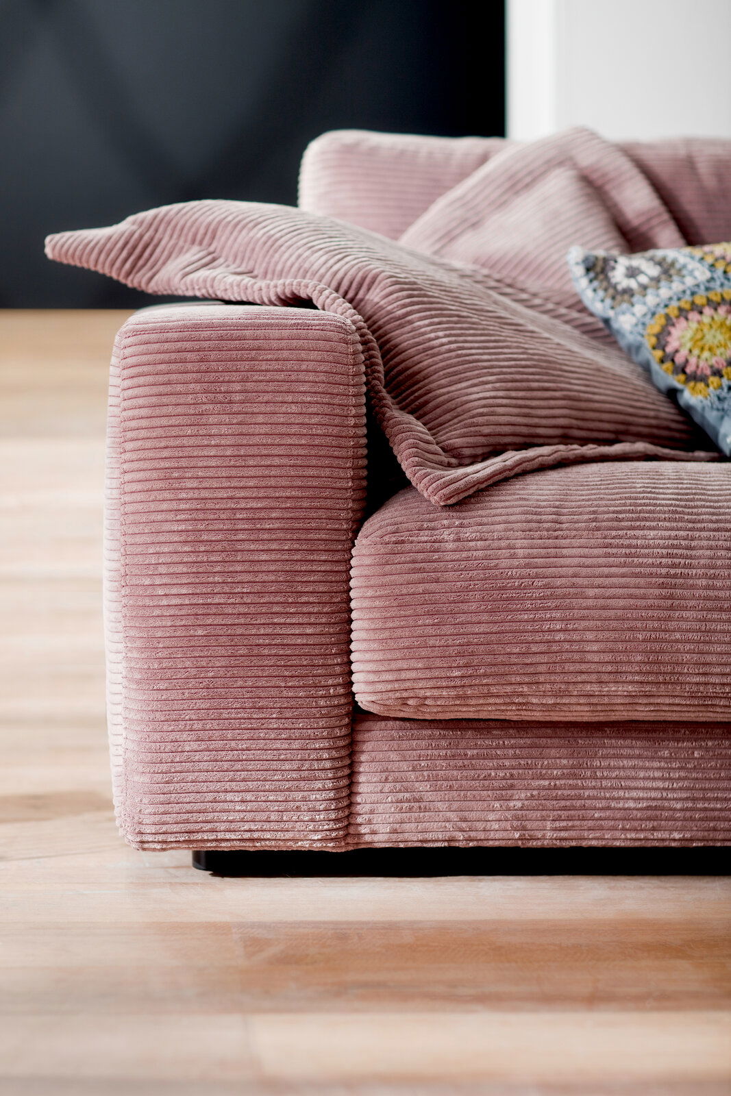 Nahaufnahme eines rosa Cord-Sofas mit Kissen, seitliche Perspektive