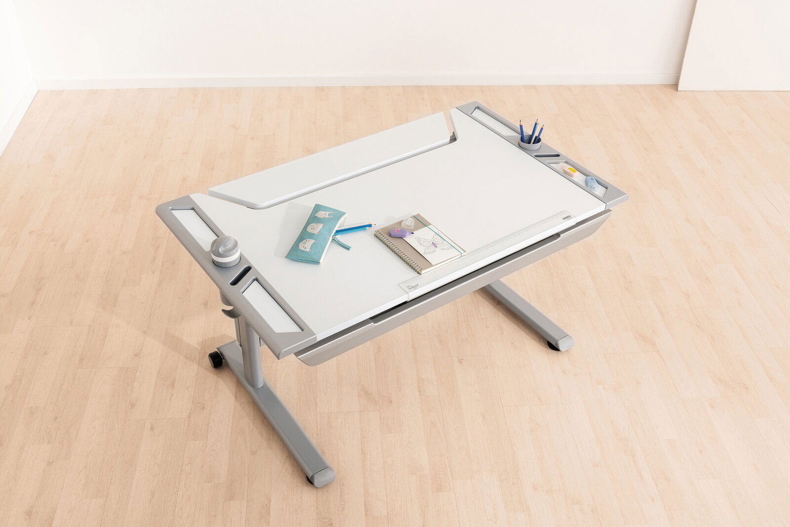 Moderner Schreibtisch mit neigbarer Arbeitsfläche, von oben fotografiert, mit Stiftehalter und Ablagefächern.