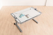 Moderner Schreibtisch mit neigbarer Arbeitsfläche, von oben fotografiert, mit Stiftehalter und Ablagefächern.