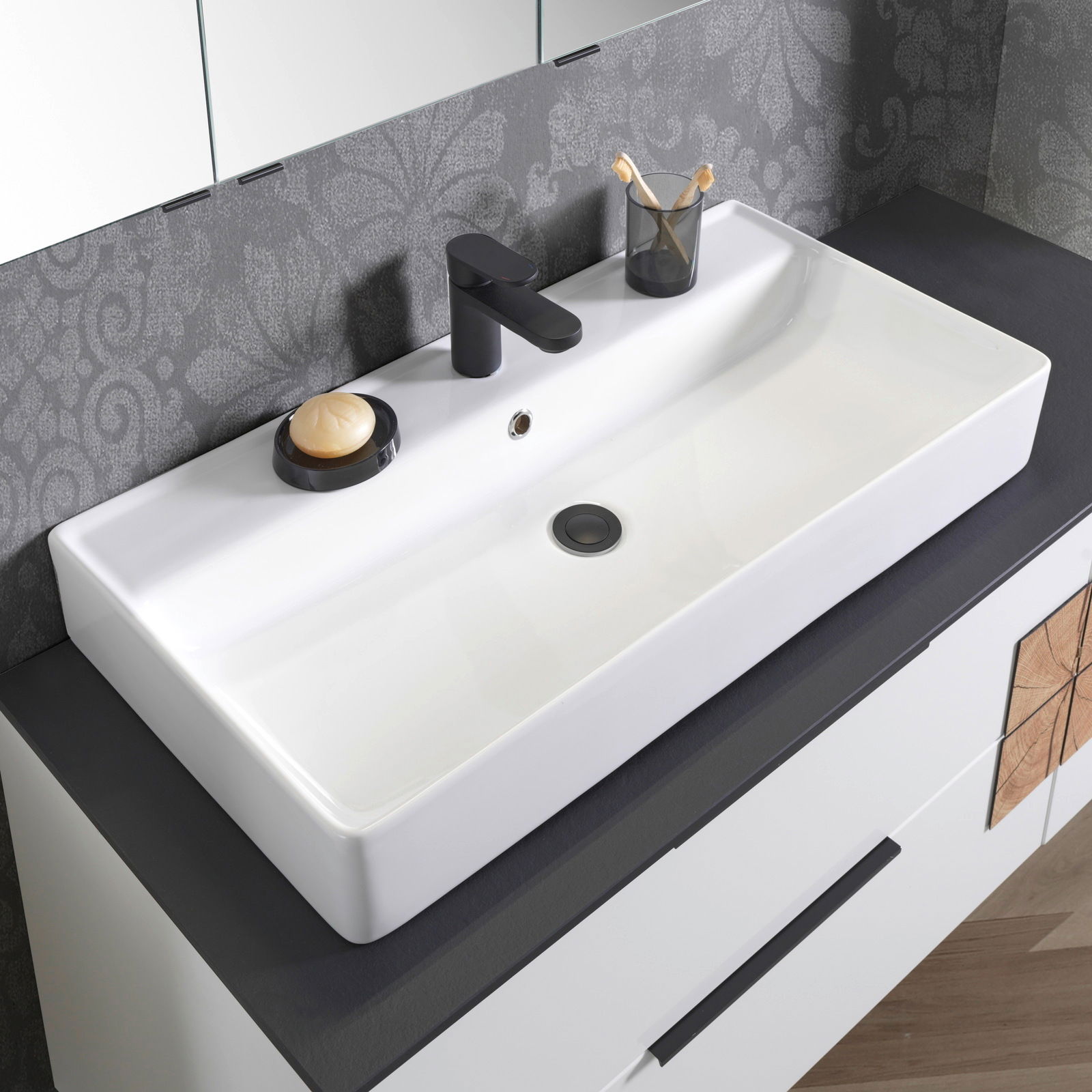 Moderner Waschtisch mit schwarzem Wasserhahn, Seifenschale und Zahnputzbecher, aus der Vogelperspektive fotografiert.