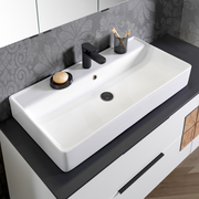 Moderner Waschtisch mit schwarzem Wasserhahn, Seifenschale und Zahnputzbecher, aus der Vogelperspektive fotografiert.