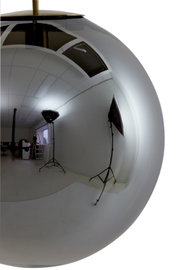 Close-up van een glanzende, bolvormige hanglamp met een reflecterend oppervlak, die een fotostudio met verlichting en camera-apparatuur toont.
