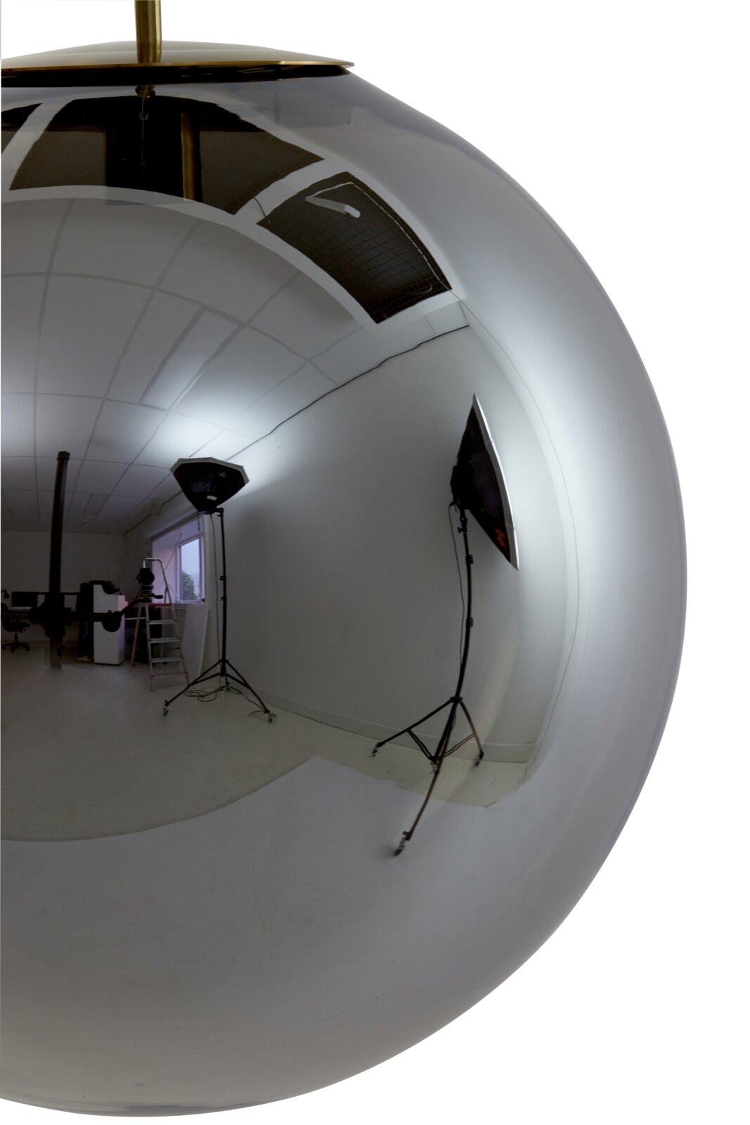 Close-up van een glanzende, bolvormige hanglamp met een reflecterend oppervlak, die een fotostudio met verlichting en camera-apparatuur toont.