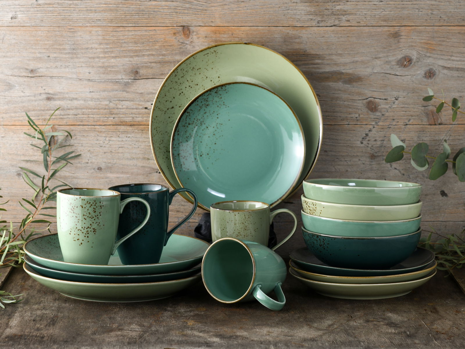 Creatable Kombiservice 16-tlg NATURE COLLECTION Kombiservice 16-tlg in verschiedenen Grüntönen, bestehend aus Tellern, Schalen und Tassen, auf rustikalem Holztisch von vorne fotografiert.
