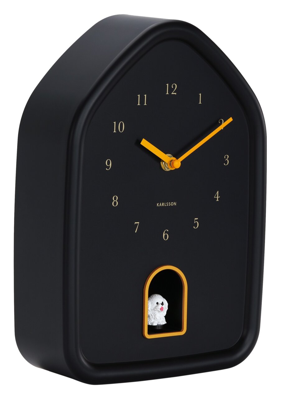 Schwarze Wanduhr in Hausform mit gelben Zeigern und einer kleinen Hundefigur in einer Öffnung unten, seitliche Perspektive.