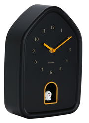 Schwarze Wanduhr in Hausform mit gelben Zeigern und einer kleinen Hundefigur in einer Öffnung unten, seitliche Perspektive.