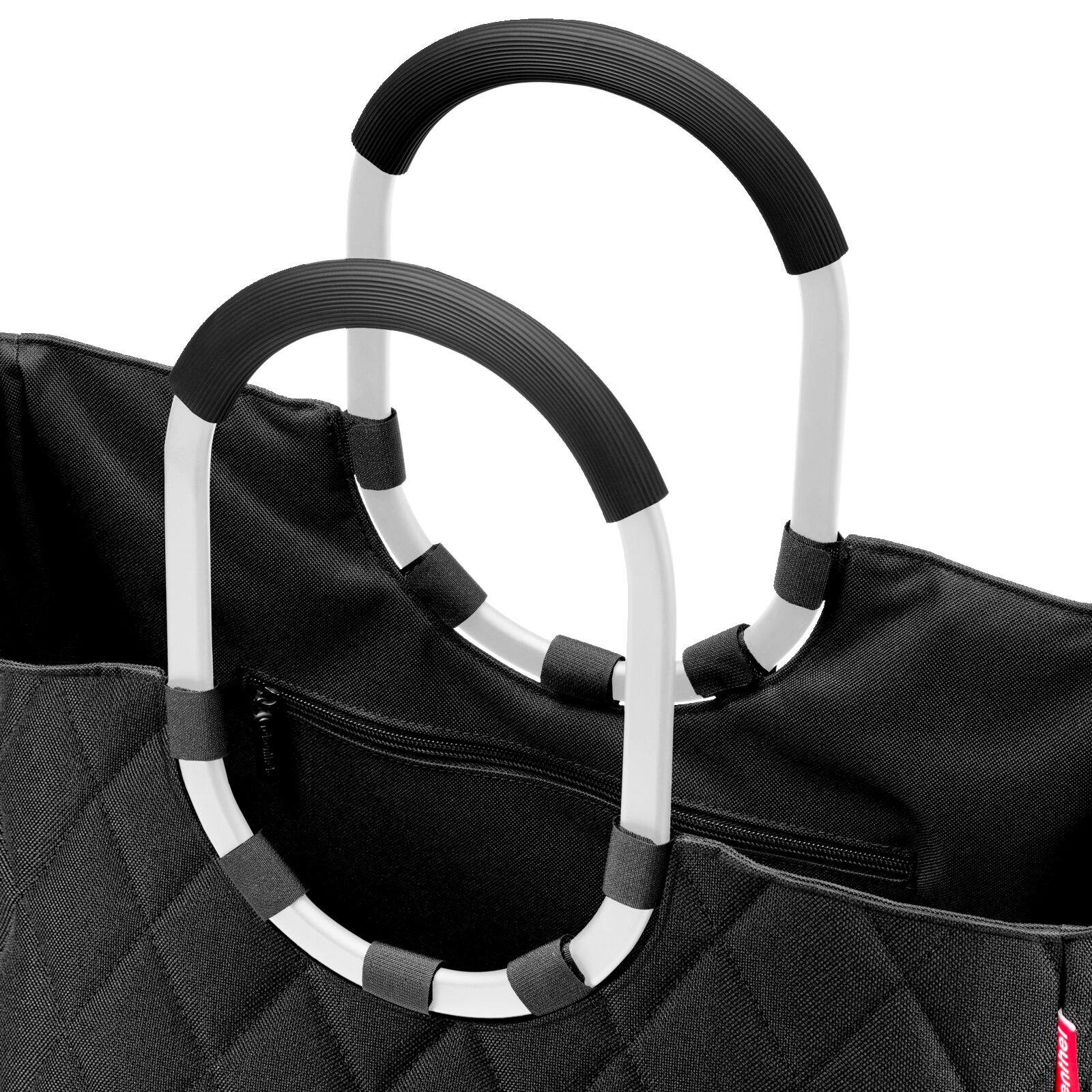 Nahaufnahme einer schwarzen Tasche mit Rautenmuster und zwei großen, ovalen Griffen in Schwarz und Weiß.