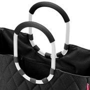 Nahaufnahme einer schwarzen Tasche mit Rautenmuster und zwei großen, ovalen Griffen in Schwarz und Weiß.