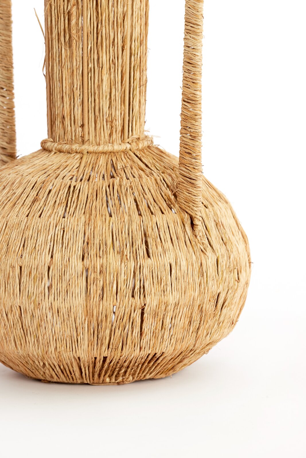 Nahaufnahme einer handgefertigten Vase aus geflochtenem Naturmaterial mit zwei Griffen, seitliche Perspektive