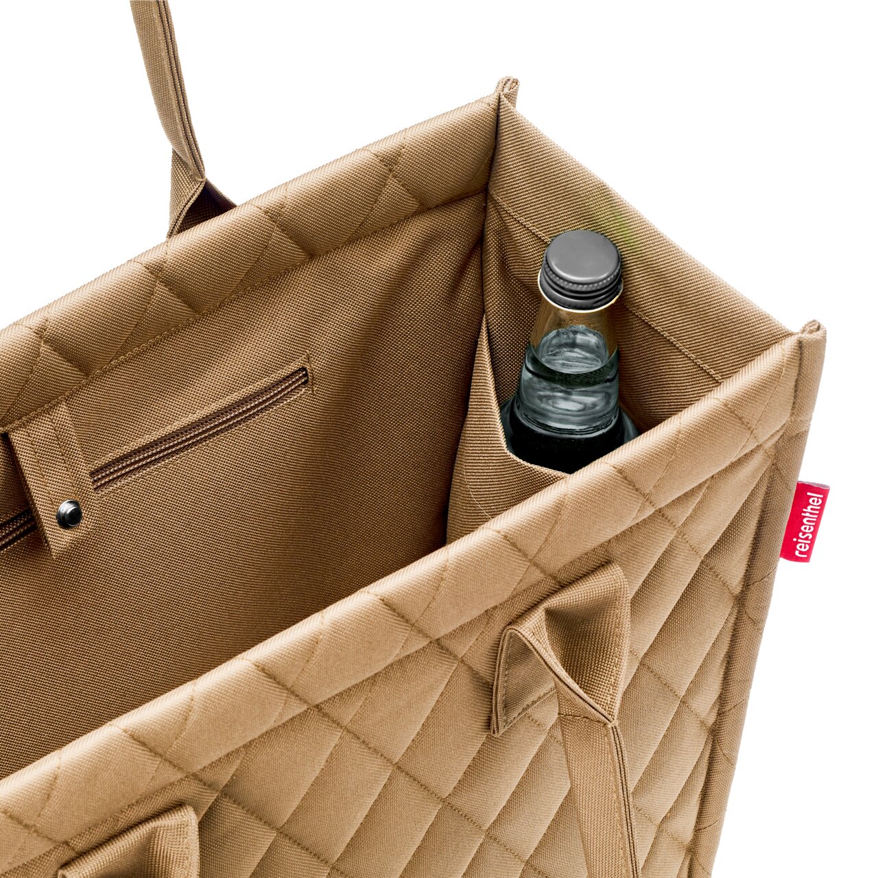 Nahaufnahme einer beigen Einkaufstasche mit Rautenmuster, die eine Flasche in einem Seitenfach zeigt. Perspektive von oben.