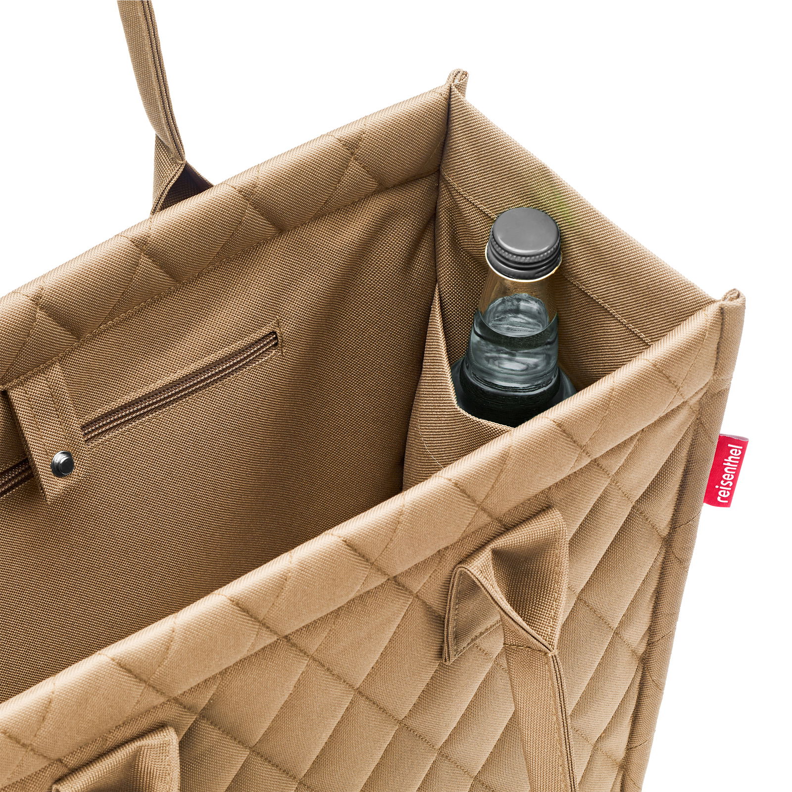 Nahaufnahme einer beigen Einkaufstasche mit Rautenmuster, die eine Flasche in einem Seitenfach zeigt. Perspektive von oben.