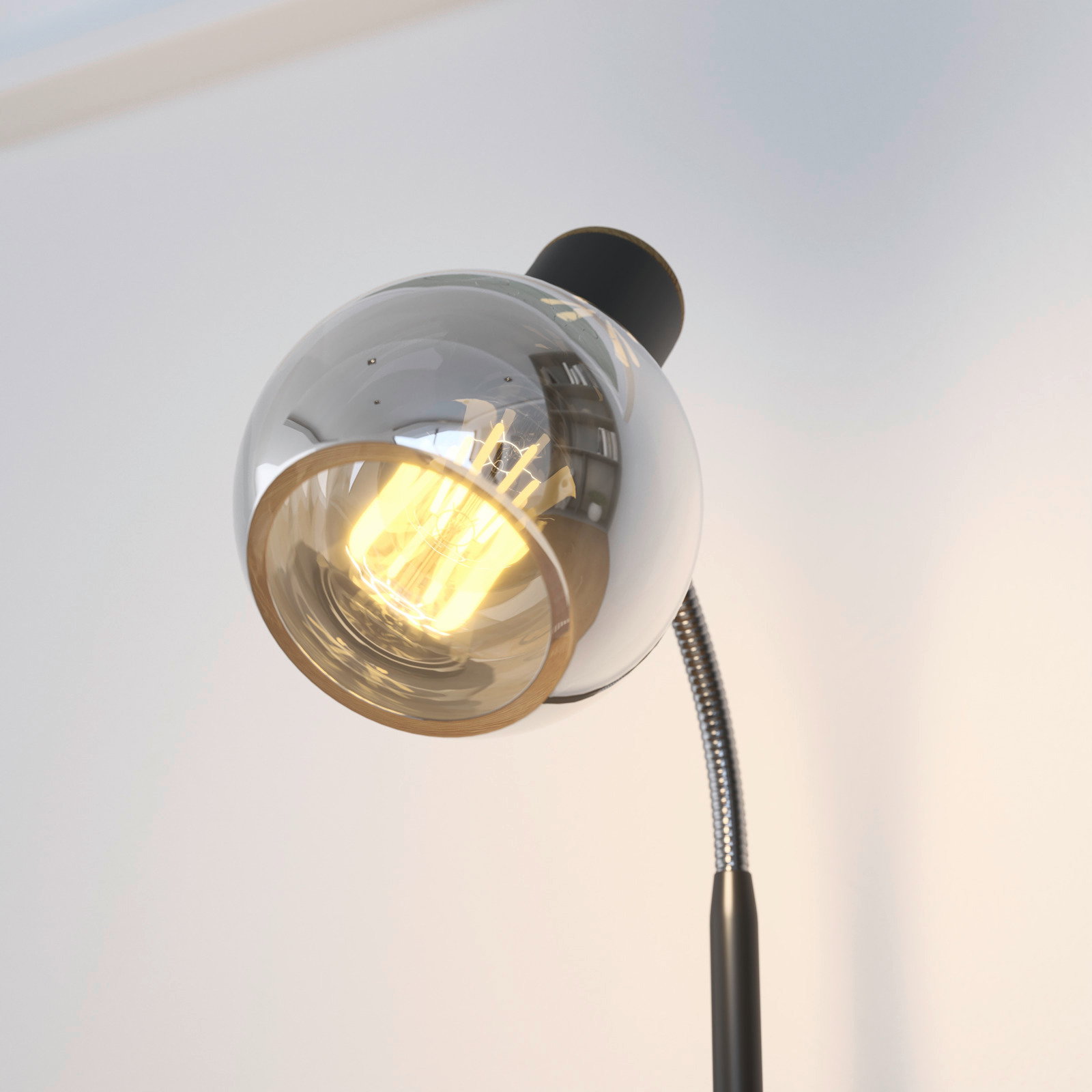 Close-up van een moderne tafellamp met een flexibele arm en een glanzende, bolvormige lampenkap.