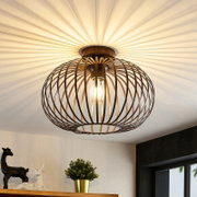 Moderne plafondlamp met een bolvormig, bronskleurig roosterontwerp, gefotografeerd van onderaf, die een warm licht op het plafond werpt.