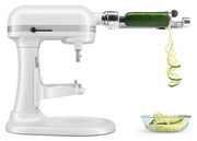 Weiße Küchenmaschine mit Spiralschneider-Aufsatz, der eine Zucchini in Spiralen schneidet, seitliche Perspektive.