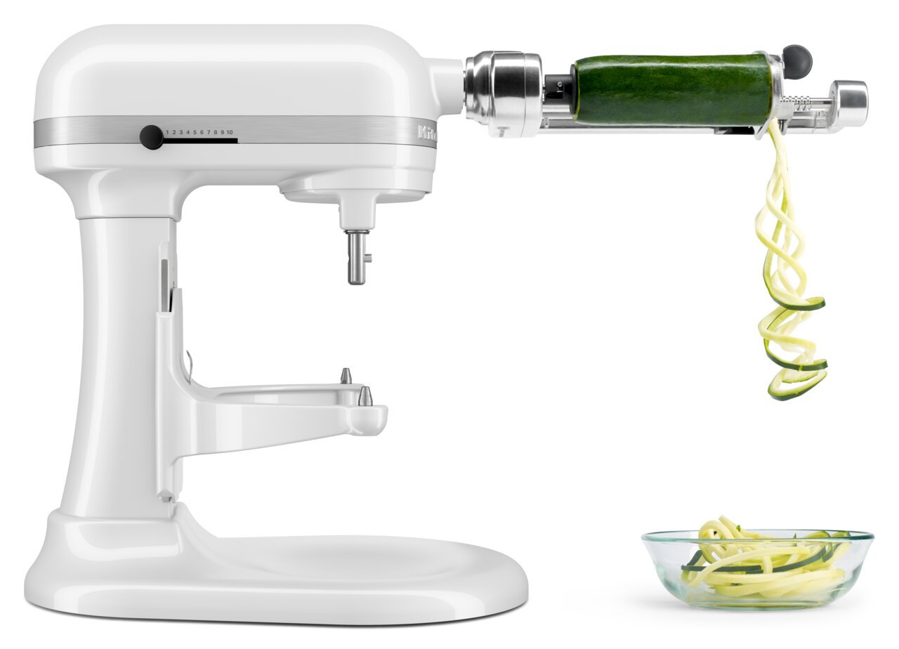 Weiße Küchenmaschine mit Spiralschneider-Aufsatz, der eine Zucchini in Spiralen schneidet, seitliche Perspektive.