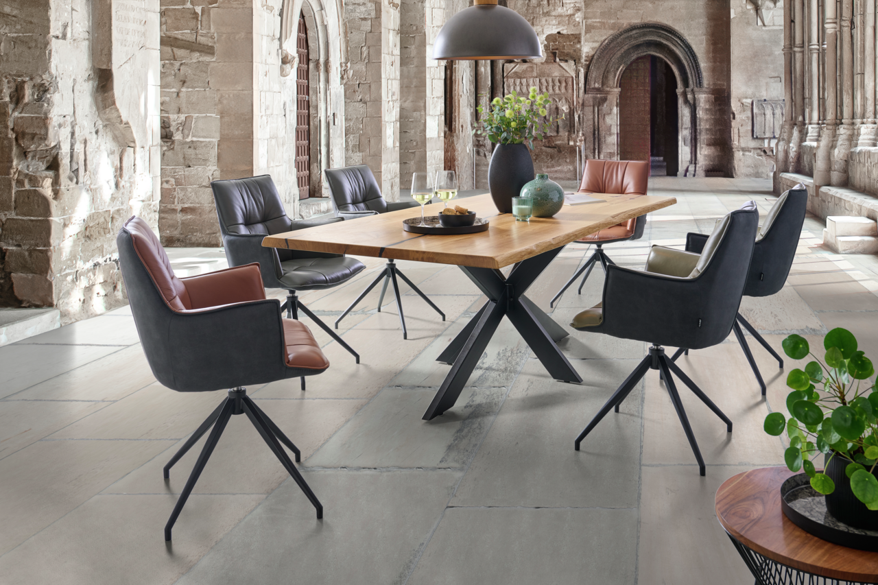 Esszimmer mit modernen Sesseln und Holztisch in einem historischen Gebäude, seitliche Perspektive