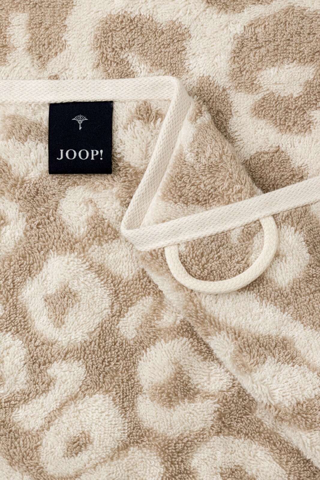 Close-up van een beige douchehanddoek met luipaardprint en een JOOP!-label.