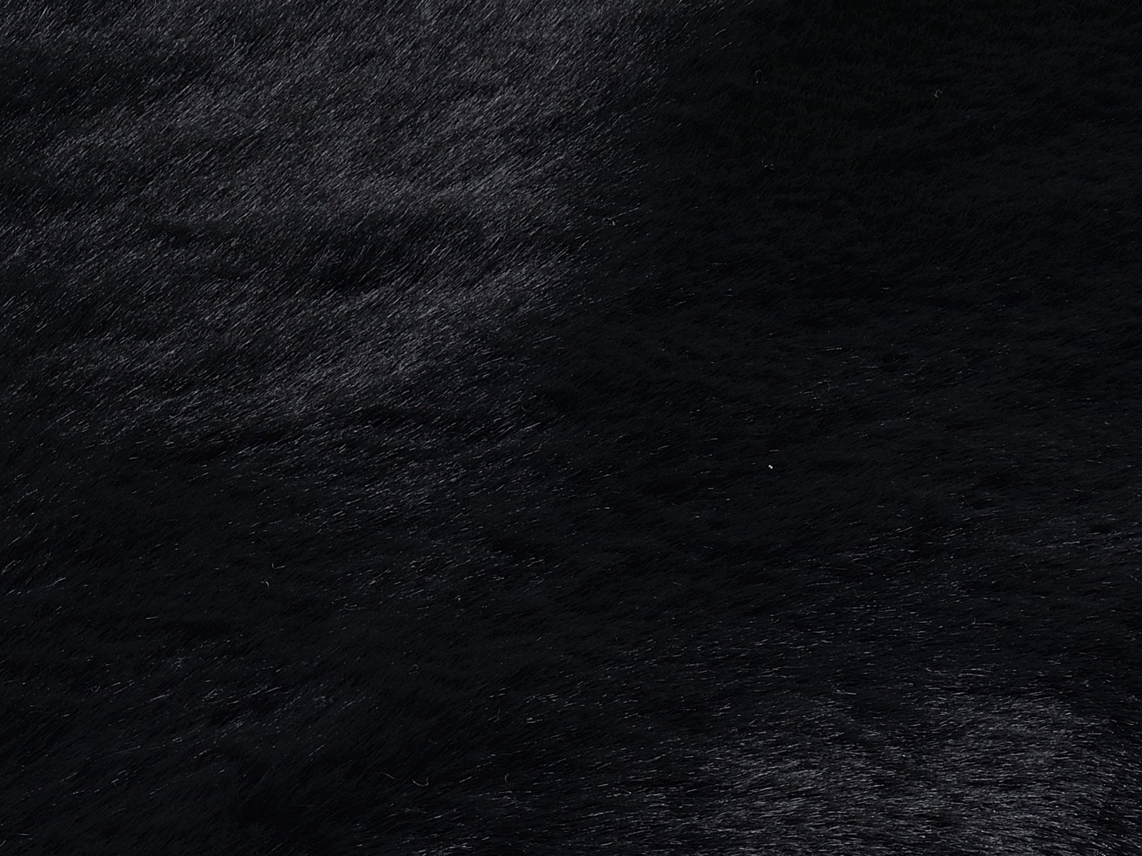 Nahaufnahme eines schwarzen Fellteppichs mit weicher Textur.