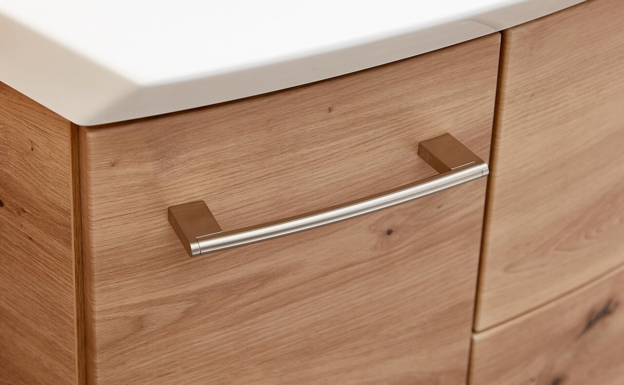 Close-up van een houten badkamerkastje met een geborstelde metalen handgreep, gezien vanaf de zijkant