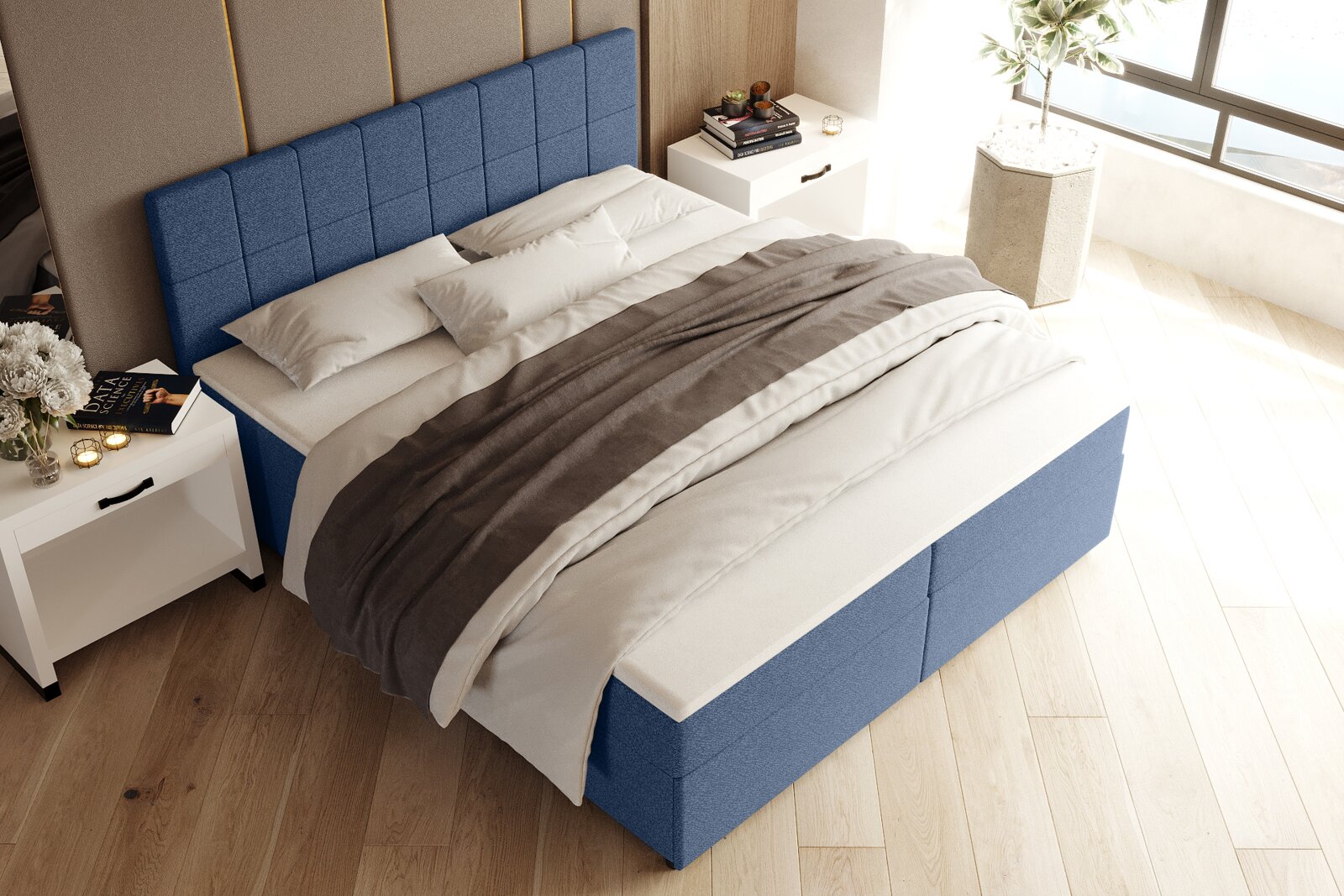 Blaues gepolstertes Boxspringbett mit gestepptem Kopfteil und weiß-grauer Bettwäsche im hellen Schlafzimmer, schräg von oben aus der Ecke fotografiert