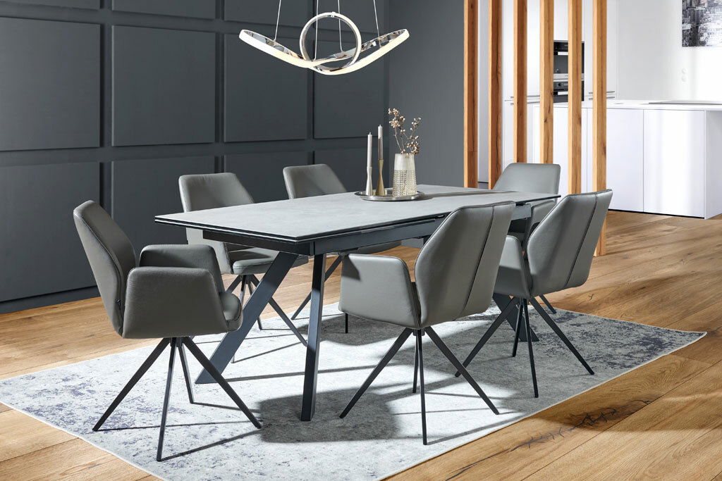 Moderner Esstisch mit grauer Tischplatte und schwarzen Metallbeinen, umgeben von sechs grauen Stühlen in einem stilvollen Esszimmer, seitliche Perspektive.