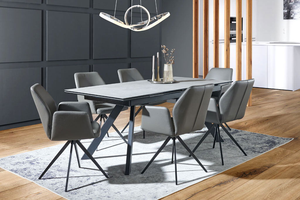 Moderner Esstisch mit grauer Tischplatte und schwarzen Metallbeinen, umgeben von sechs grauen Stühlen in einem stilvollen Esszimmer, seitliche Perspektive.
