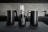 Drei schwarze Küchengeräte auf einer Arbeitsplatte, darunter zwei Wasserkocher und ein Mixer, frontal fotografiert.