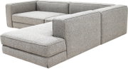 Moderne grijze stoffen hoekbank met chaise longue aan de linkerkant en brede armleuningen, schuin van voren rechts gezien
