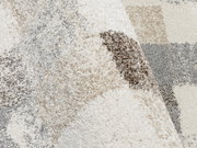 Nahaufnahme eines Frisé-Teppichs mit gemusterten Beige- und Grautönen, von oben betrachtet.