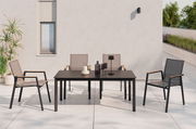 Moderner Stapelstuhl aus Metall und Textil mit Armlehnen, auf einer Terrasse neben einem Tisch, aus der Frontalperspektive.
