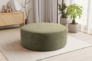 Runder, olivgrüner Cord-Sitzpouf im Wohnzimmer auf hellem Teppich, seitliche Perspektive auf das Produkt.