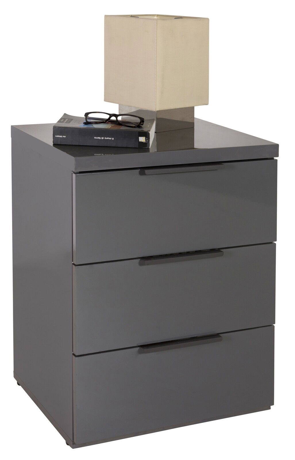 Graue Nachtkonsole mit drei Schubladen, darauf eine quadratische Lampe und ein Buch, seitliche Perspektive