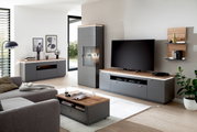 Moderne Wohnzimmermöbel in grauer und holzfarbener Optik, bestehend aus Sideboard, Wandkombination und Couchtisch, aus der Perspektive eines gemütlichen Wohnzimmers.