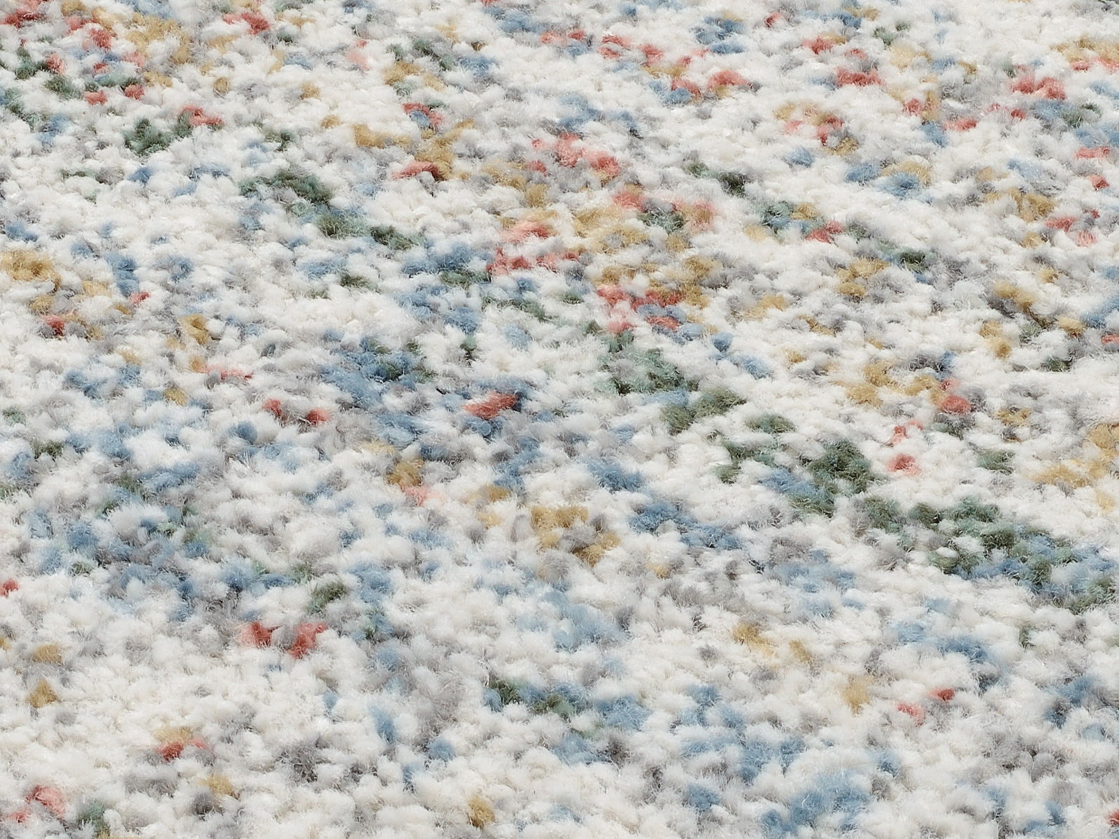 Nahaufnahme eines bunten Frisé-Teppichs mit einer Mischung aus weißen, blauen, grünen, roten und gelben Fasern, aus einer schrägen Perspektive aufgenommen.