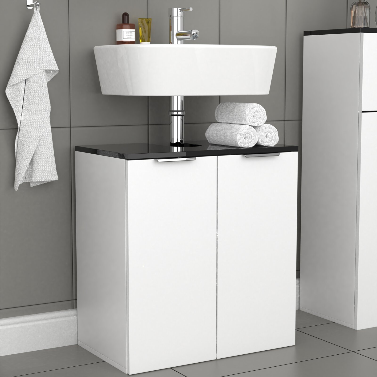 Modernes Badezimmer-Waschbecken aus weißer Keramik auf weißem Unterschrank mit schwarzer Ablage und Chromarmatur, frontale Ansicht auf Augenhöhe.