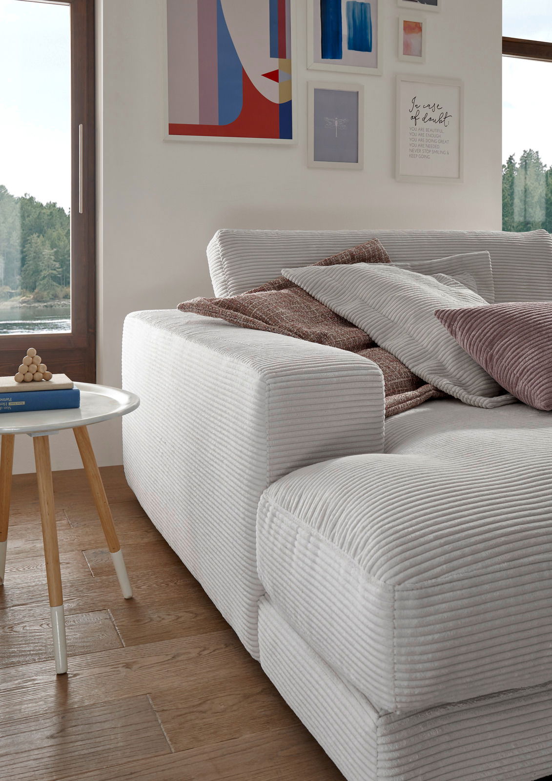 Nahaufnahme eines kleinen Megasofas in einem modernen Wohnzimmer, mit mehreren Kissen und einem Beistelltisch, aus seitlicher Perspektive.