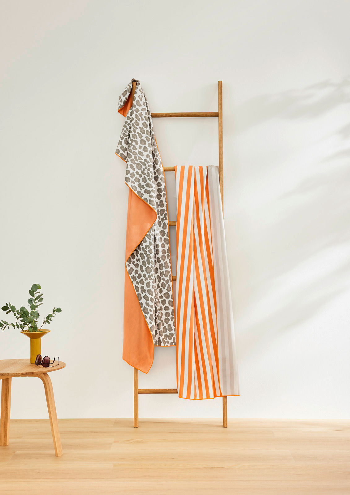 Gestreiftes Sporttuch in Orange und Weiß, aufgehängt an einer Holzleiter, seitliche Perspektive