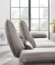 Graue Longchairkombination in einem modernen Wohnzimmer mit großen Fenstern, seitliche Perspektive.