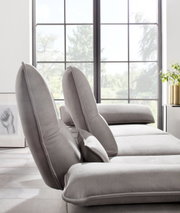 Grijze longchair-set in een moderne woonkamer met grote ramen, gezien vanaf de zijkant.