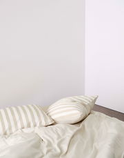 Bettwäsche-Set mit beigen und weißen Streifen, bestehend aus einem Kissenbezug und einer Bettdecke, aus der Perspektive von oben fotografiert.